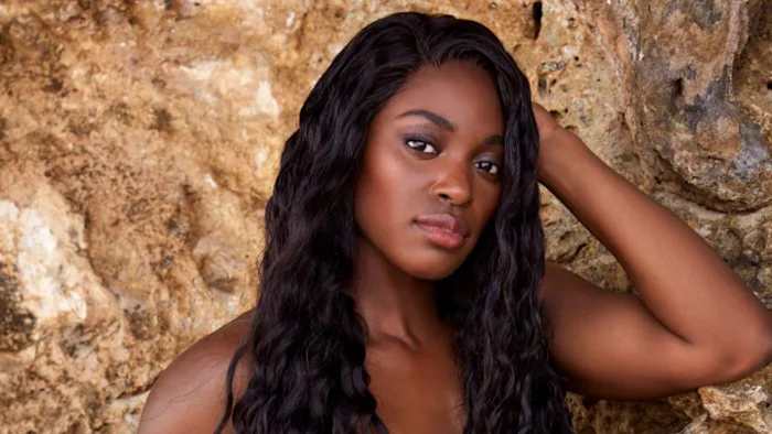 Sloane Stephens poses in front of the natural rocks with her black hair in a beach wave.